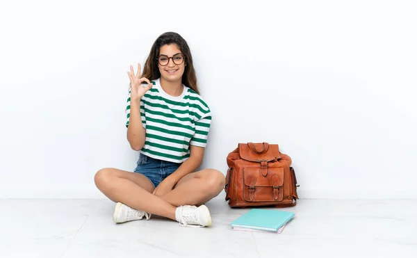 Joven Estudiante Sentada Uno Suelo Aislado Sobre Fondo Blanco Mostrando —  Fotos de Stock