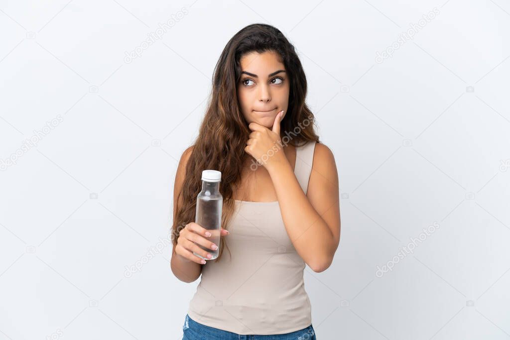Young caucasian woman with a bottle of water isolated on white background having doubts and thinking