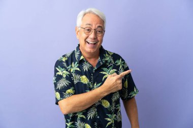 Mor arka planda izole edilmiş orta yaşlı Brezilyalı adam şaşırmış ve işaret ediyor.