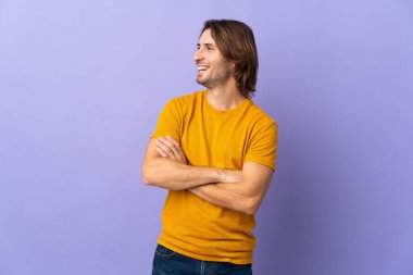 Mor arka planda izole edilmiş genç yakışıklı adam mutlu ve gülümsüyor.