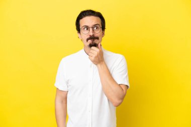 Sarı arka planda soyutlanmış genç beyaz bir adamın şüpheleri ve düşünceleri var.