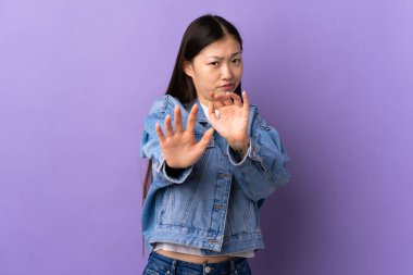 Mor arka planda izole edilmiş genç Çinli kız ellerini öne uzatarak gergin.