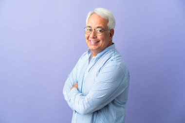Middle age Brazilian man isolated on purple background with arms crossed and looking forward