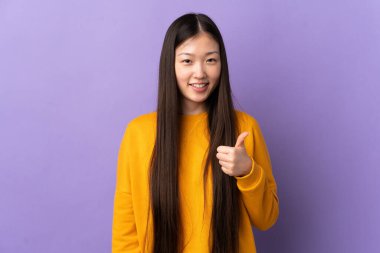 Soyutlanmış mor arka planda genç bir Çinli kız baş parmak işareti yapıyor.