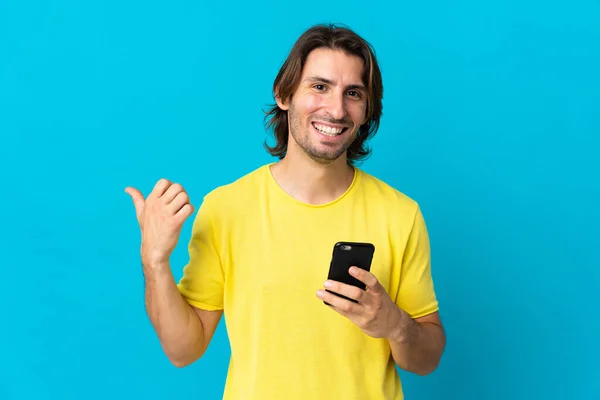 Young Handsome Man Isolated Blue Background Using Mobile Phone Pointing — Stock Photo, Image