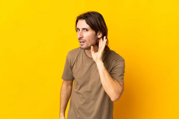 Joven Hombre Guapo Aislado Sobre Fondo Amarillo Escuchando Algo Poniendo —  Fotos de Stock