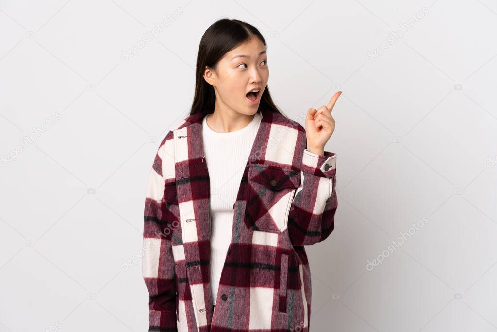 Young Chinese girl over isolated white background intending to realizes the solution while lifting a finger up