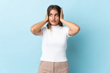 Genç Uruguaylı kadın mavi arka planda izole edilmiş hayal kırıklığına uğramış ve kulaklarını kapatmış