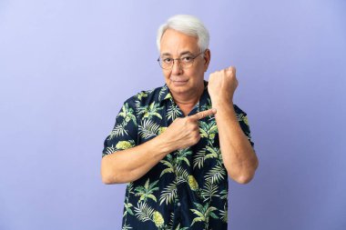 Middle age Brazilian man isolated on purple background making the gesture of being late