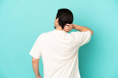 Kafkasyalı genç adam mavi arka planda izole edilmiş ve düşünüyor.