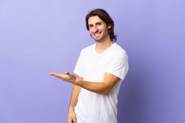 Mor arka planda soyutlanmış genç yakışıklı bir fikir sunuyor ve gülümsüyor.