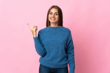 Pembe arka planda izole edilmiş genç Uruguaylı kadın en iyinin işareti olarak parmağını kaldırıyor.