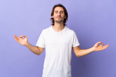 Mor arka planda, Zen pozisyonunda izole genç yakışıklı bir adam.