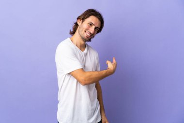 Mor arka planda izole genç yakışıklı adam geriye işaret ediyor