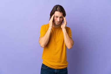 Mor arka planda başı ağrıyan genç ve yakışıklı bir adam.