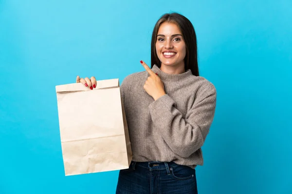 Woman Taking Bag Takeaway Food Isolated Blue Background Pointing Side — Photo