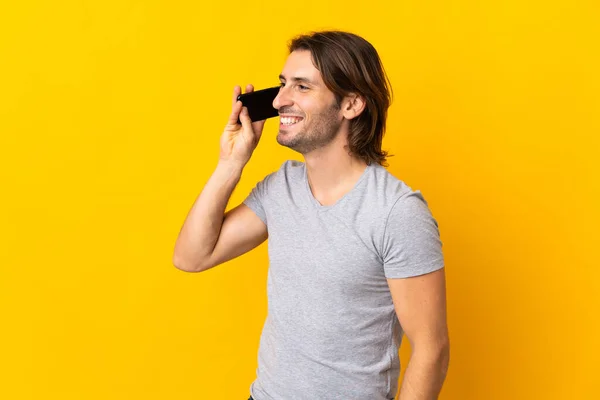 Молодой Красивый Мужчина Изолированный Желтом Фоне Поддерживает Разговор Мобильным Телефоном — стоковое фото