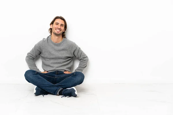 Young Handsome Man Sitting Floor Isolated Background Posing Arms Hip — Stock Photo, Image