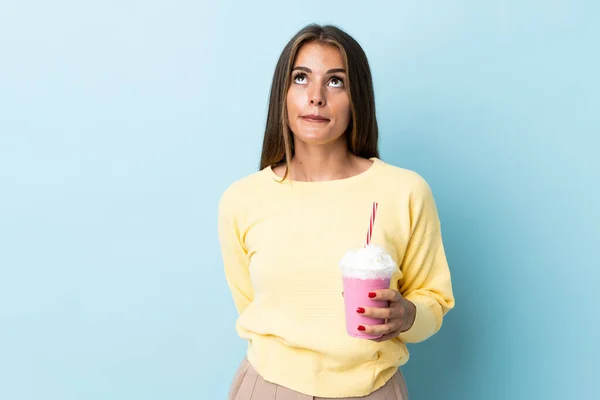 Young Uruguayan Woman Strawberry Milkshake Isolated Blue Background Looking — Stock Fotó