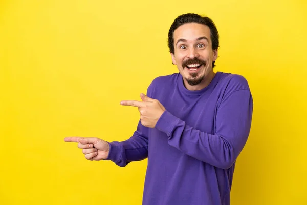 Junge Kaukasische Mann Isoliert Auf Gelbem Hintergrund Überrascht Und Zeigt — Stockfoto