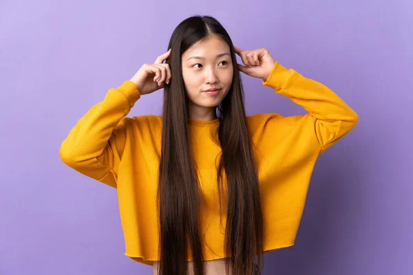 一个有着怀疑和思考的紫色背景的年轻中国女孩 — 图库照片