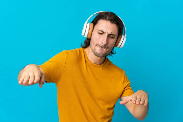 Joven Hombre Guapo Aislado Sobre Fondo Azul Escuchando Música Bailando —  Fotos de Stock