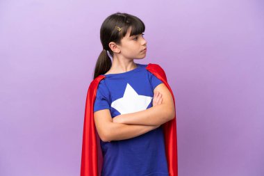 Mor arka planda, kolları bağlı, süper kahraman kostümlü küçük bir çocuk.
