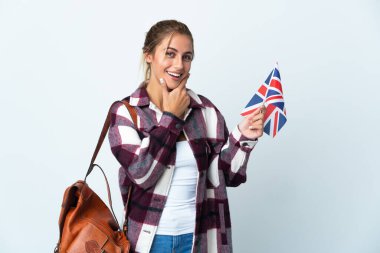 Beyaz arka planda izole edilmiş İngiliz bayrağı taşıyan genç bir kadın mutlu ve gülümsüyor.