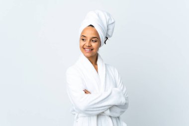 Bornozlu genç bir kadın soyutlanmış beyaz arka planda yan tarafa bakıyor ve gülümsüyor.