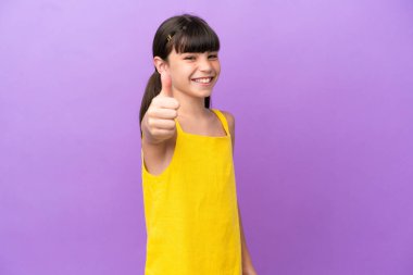 Küçük beyaz çocuk mor arka planda izole edildi. Başparmakları havada çünkü iyi bir şey oldu.