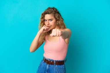 Mavi arka planda, savaşan genç sarışın kadın.