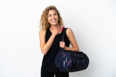 Spor çantalı genç bayan beyaz arka planda izole edilmiş gülümserken yukarı bakıyor