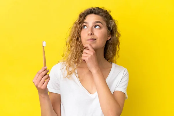 Młoda Biała Kobieta Trzymająca Szczotkujące Zęby Wyizolowane Żółtym Tle Patrząca — Zdjęcie stockowe