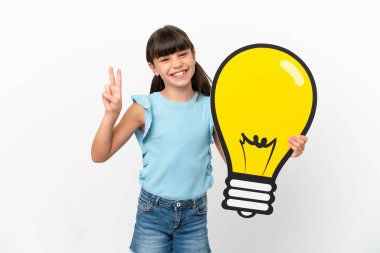 Beyaz arka planda izole edilmiş beyaz bir çocuk elinde bir ampul simgesi tutarak zaferi kutluyor.