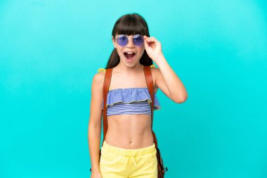 Küçük beyaz çocuk plaja gidiyor mavi arka planda gözlüklü ve şaşırmış.