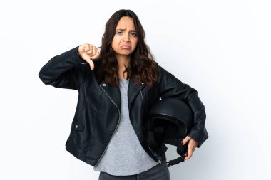 İzole edilmiş beyaz arka planda motosiklet kaskı tutan genç bir kadın baş parmağını aşağı gösteriyor.