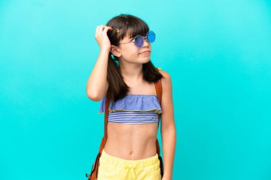 Kafkasyalı küçük bir çocuk kumsala gidiyor. Mavi arka planda izole edilmiş. Şüpheleri var ve kafası karışık.