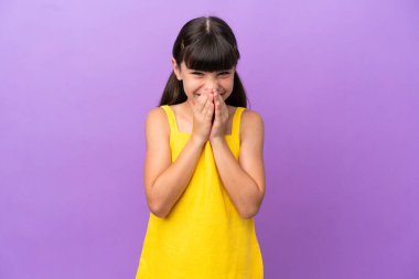 Küçük beyaz çocuk mor arka planda izole edilmiş mutlu ve gülümseyen elleriyle ağzını kapatıyor.