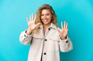 Mavi arka planda izole edilmiş genç sarışın kadın parmaklarıyla dokuzu sayıyor.