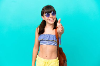 Küçük beyaz bir çocuk kumsala gidiyor. Mavi arka planda izole edilmiş, iyi bir anlaşma için el sıkışıyor.