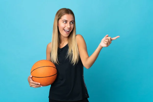 年轻女子打篮球时被白色背景隔离 手指指向旁边 并展示了一种产品 — 图库照片