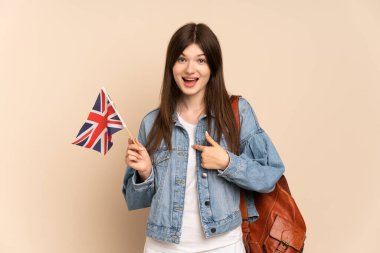 Ukraynalı genç bir kız, elinde bej arka planda izole edilmiş bir Birleşik Krallık bayrağı tutuyor.