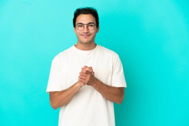 Kafkasyalı yakışıklı adam soyutlanmış mavi arka planda gülüyor.