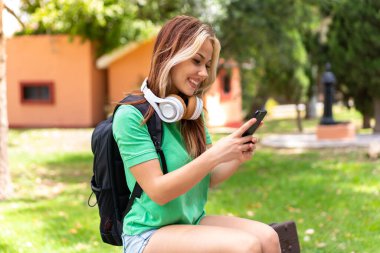 Dışarıda cep telefonu kullanan genç bir bayan öğrenci.