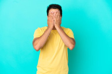 Kafkas yakışıklı adam izole edilmiş mavi arka planda gözlerini elleriyle kapatıyor.