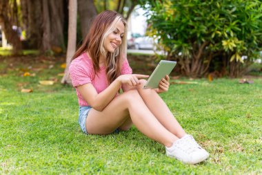 Dışarıda elinde tabletle bekleyen genç ve güzel bir kadın.