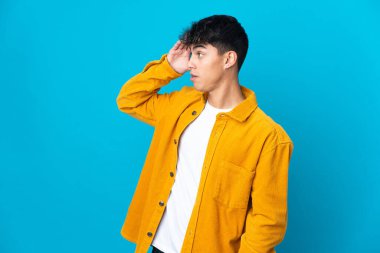 Yalıtılmış mavi arka planı olan genç bir adam.