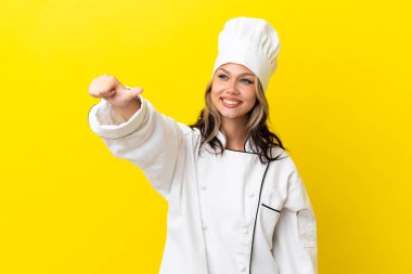 Sarı arka planda izole edilmiş genç bir Rus şef kız baş parmak işareti yapıyor.