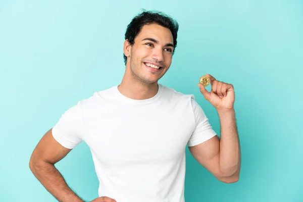 Młody Mężczyzna Trzyma Bitcoin Nad Odizolowanym Niebieskim Tle Pozowanie Ramionami — Zdjęcie stockowe