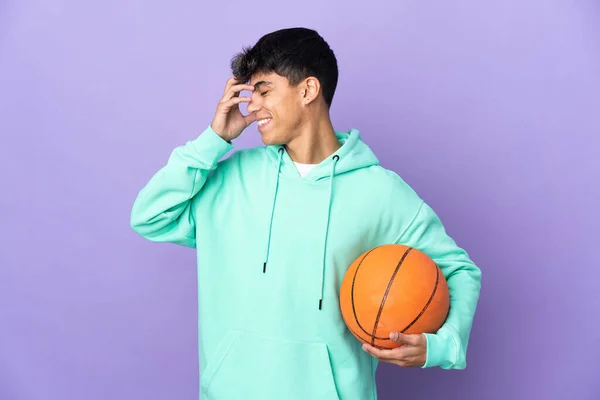 在孤立的紫色背景下打篮球的年轻人笑着 — 图库照片